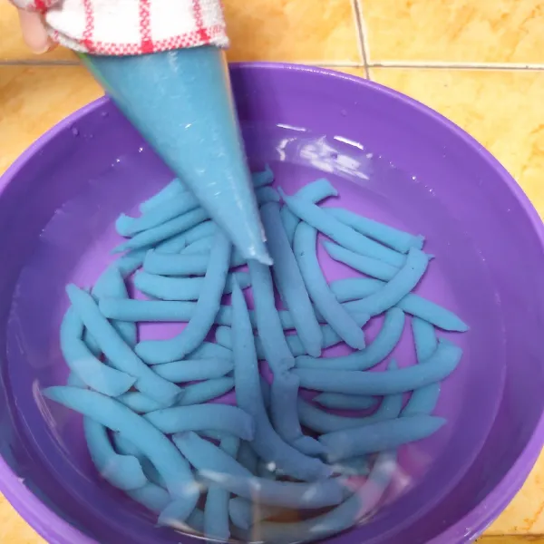Selanjutnya masukkan adonan kedalam plastik segitiga, semprotkan kedalam air es sedikit demi sedikit sampai semua adonan habis.