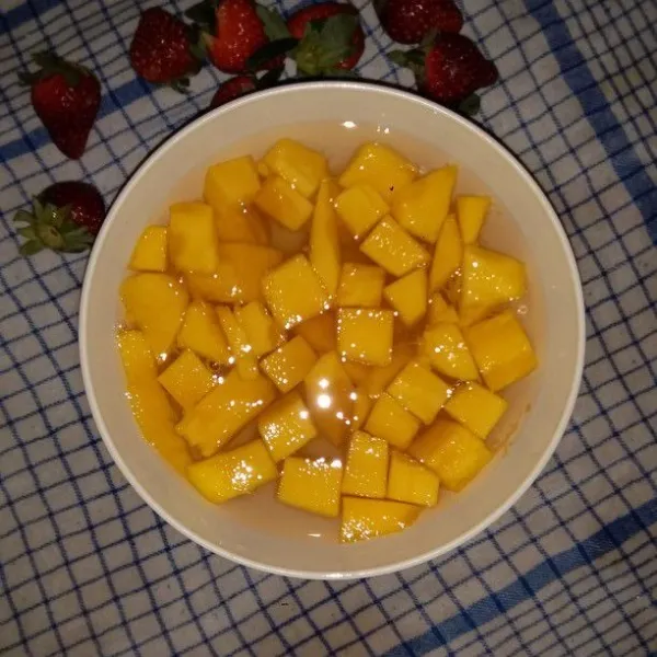 Siapkan mangkok saji. Tuang air gula dan masukkan potongan buah mangga.