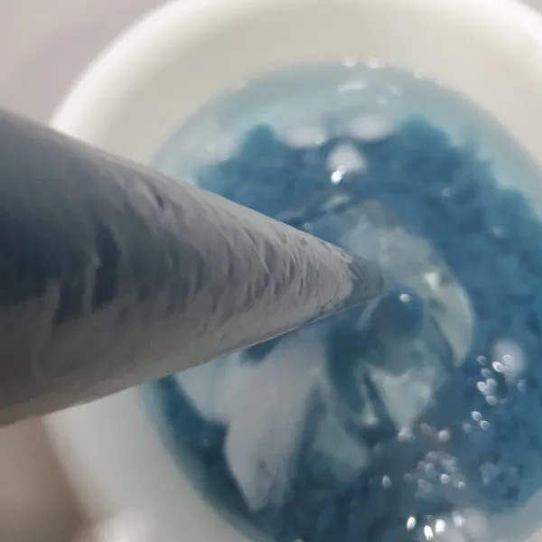 Masukkan adonan ke dalam plastik piping bag, gunting sedikit bagian ujungnya, lalu semprotkan hingga adonan cendol/dawet jatuh kedalam air dingin yang di campur dengan es batu.