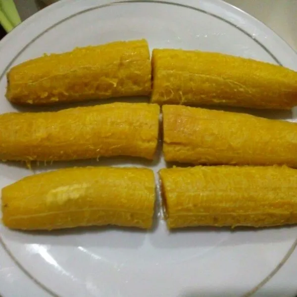Kupas pisang yang telah dikukus, potong masing-masing jadi 2 bagian. Sisihkan.