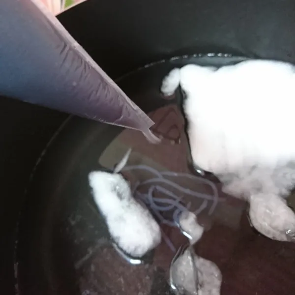 Masukkan ke dalam plastik segitiga, potong ujungnya lalu semprotkan ke dalam baskom yg berisi air es.