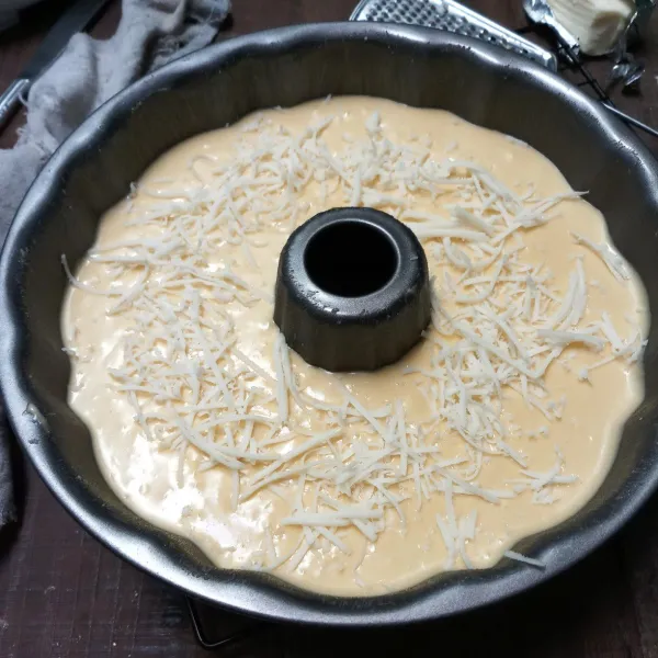 Tuang ke loyang yang sudah dioles carlo (olesan loyang), beri topping keju parut