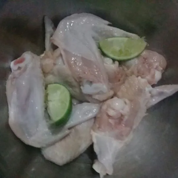 Potong sayap ayam menjadi 2 bagian, lalu beri perasan air jeruk nipis, diamkan selama 10 menit, lalu cuci bersih.