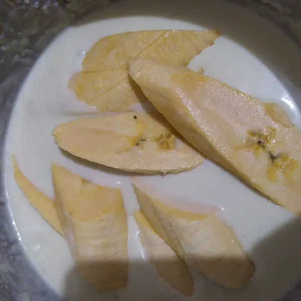 Mulai panaskan minyak dalam wajan. Kupas pisang, potong serong pisang, celupkan pisang ke dalam adonan.