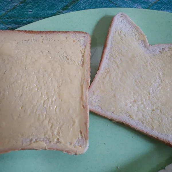 Olesi roti tawar menggunakan margarin.