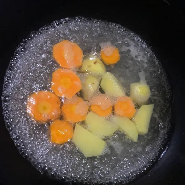 Potong kecil kentang dan wortel lalu rebus hingga matang.