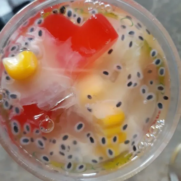 Siapkan es batu. Masukkan dalam gelas bersama jelly mangga, kolang kaling, selasih, dan jagung. Siram dengan 1 gelas air dan susu kental manis. Aduk rata.