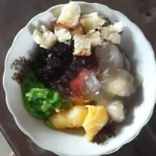 Siapkan mangkuk saji, masukkan es batu, bubur sumsum, ketan hitam, jenang grendul, dawet, mutiara, tape singkong dan roti.