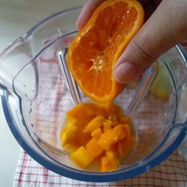 Siapkan gelas blender. Masukan buah mangga beku, gula pasir, air matang, dan perasan air jeruk.