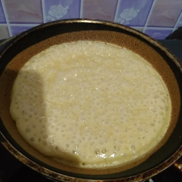 Tuang di teflon yang sudah dipanaskan. Masak dengan api kecil sampai keluar gelembung. Lalu taburi dengan gula pasir. Kemudian tutup dan masak sampai matang.