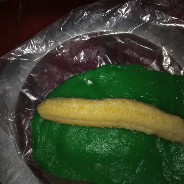 Ambil sedikit adonan lalu pipihkan masukkan pisang yang sudah dikupas lalu gulung masukkan ke dalam daun lalu giling dan tusuk dengan lidi.