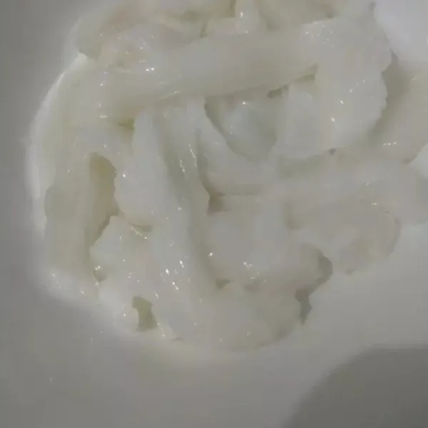 Serut daging kelapa muda dengan tutup botol sprite taruh di wadah bersih.