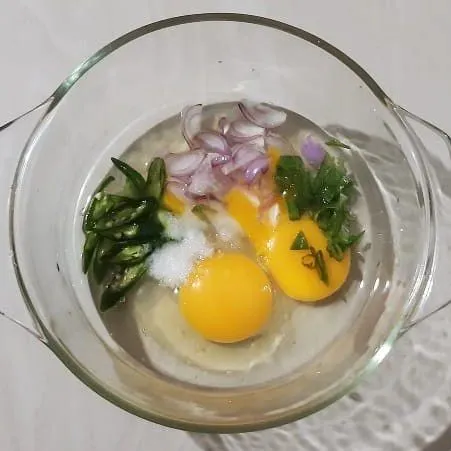 Dalam sebuah mangkuk masukan telur, bawang merah, daun bawang, cabai keriting, garam, dan vetcin. Kocok hingga semua bahan tercampur.
