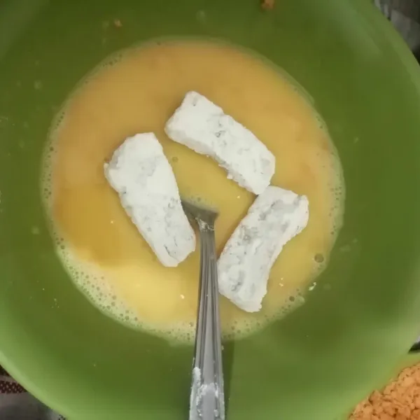 Balur potongan nugget ke dalam tepung terigu, lalu ke dalam kocokan telur.