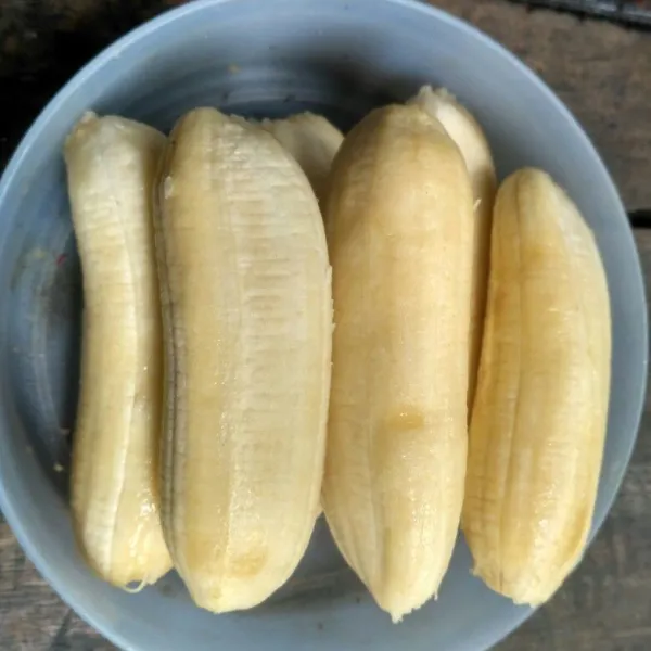 Kupas pisang dan gosok-gosok bagian luarnya agar terlihat licin.