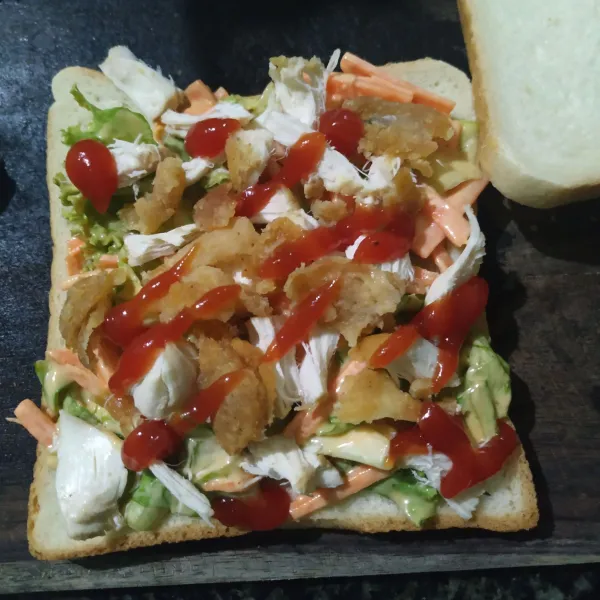 Tata roti beri selada diatasnya dan suwiran ayam beri saos tomat diatasnya, tutup dengan roti.