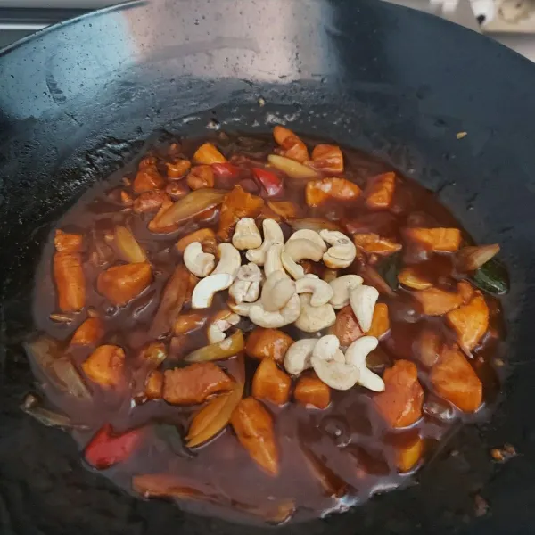Tambahkan kacang mede panggang dan daun bawang, koreksi rasa. Masak sampai air menyusut.