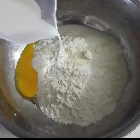 Campur tepung terigu dan telur, tuang susu cair dan aduk rata.