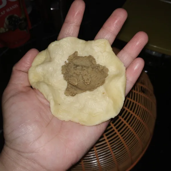 Bagi adonan roti menjadi bulatan kecil. Kemudian pipihkan bagian pinggirnya, masukkan isian di bagian tengah. Tutup dan bentuk bulat lagi.