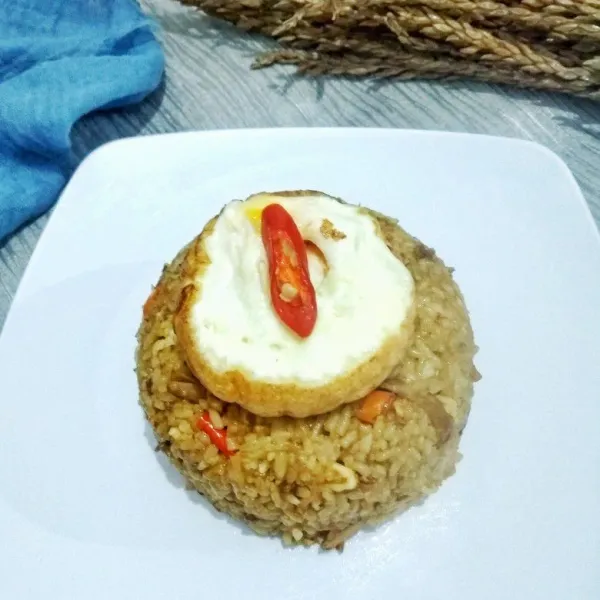 Sajikan dengan tambahan telur dadar di atasnya. Nasi goreng spesial siap disantap.