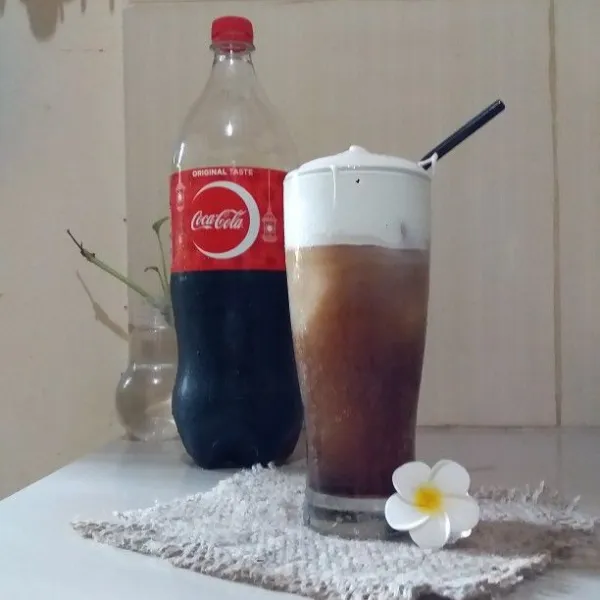 Masukkan whipped cream ke dalam piping bag. Gunting ujungnya lalu semprotkan ke atas coca-cola.