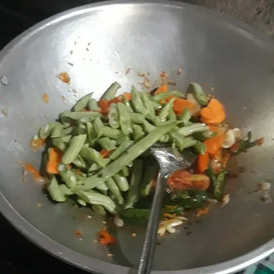 Masukkan buncis, wortel tumis sambil diaduk hingga setengah matang.
