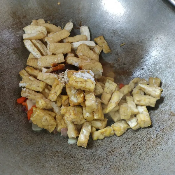 Selanjutnya masukkan tahu, tempe, dan air. Bumbui dengan gula, garam, saus teriyaki, dan kaldu jamur. Aduk hingga tercampur rata.