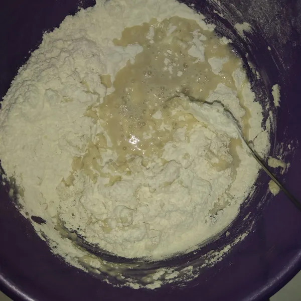 Campurkan ragi ke dalam wadah yang berisi tepung. Uleni sampai tercampur.