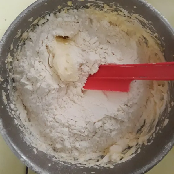Masukkan tepung terigu, susu bubuk, dan keju edam parut sampai tercampur rata. Aduk dengan menggunakan spatula