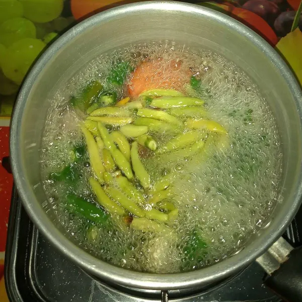 Rebus air sampai mendidih, bubuhi sedikit garam. Rebus cabe hijau, cabe rawit, tomat, bawang merah dan bawang putih sebentar.