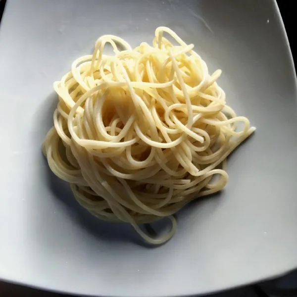 Tata rapi spaghetti ke dalam piring dan tambahkan saus bolognaise