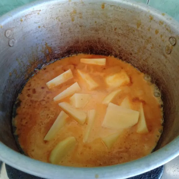 Tambahkan air, lalu masukkan potongan kentang. Rebus bersama bumbu hingga 1/2 lunak.