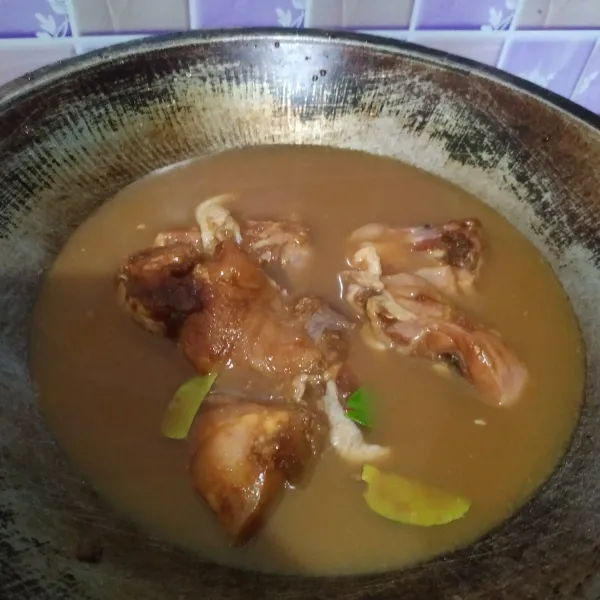 Taruh daun salam dan daun jeruk di dasar wajan. Masukkan campuran ayam berbumbu. Beri air secukupnya.
