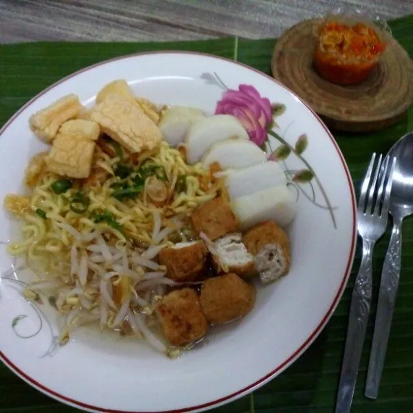 Tata dalam piring saji: mie, lontong, tahu, tauge, potongan kerupuk gendar. Beri kuah kaldu bersama pelengkap.