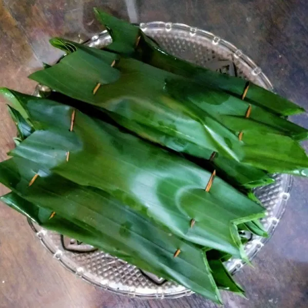 Gulung semua daun pisang yang telah berisi ikan dan bumbu, kemudian tusuk bagian ujung-ujung daun dengan lidi, rapikan dengan gunting.