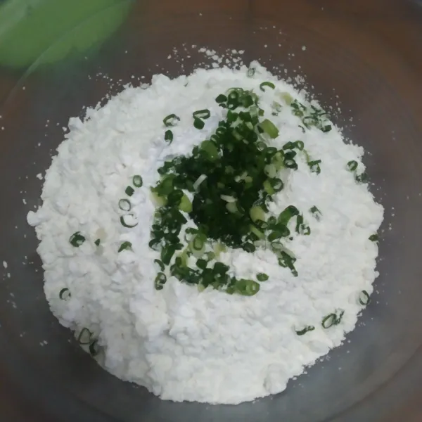 Tambahkan irisan daun bawang pada tepung, aduk asal.