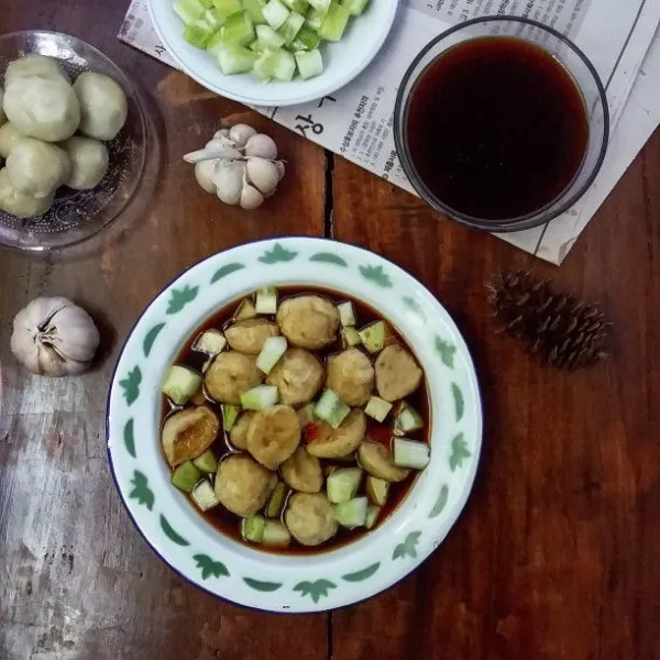 Siapkan piring saji. Masukan potongan pempek. Tambahkan irisan timun. Siram kuah cuko secukupnya