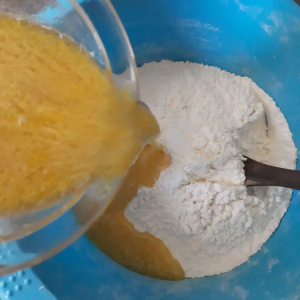 Campur tepung terigu dan garam di dalam baskom. Tuang ragi, aduk dengan spatula kayu.