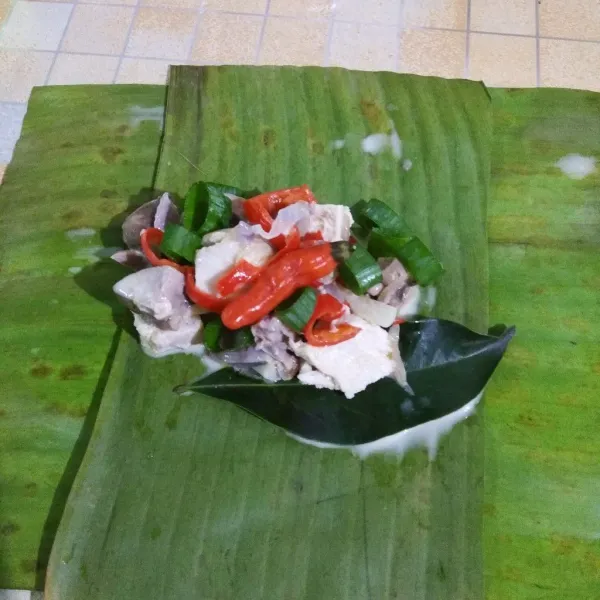 Siapkan daun pisang untuk membungkus. Letakan daun salam, taburi daun bawang, beri cabe rawit.