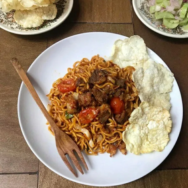Sajikan mie aceh goreng bersama emping, acar timun dan bawang merah.