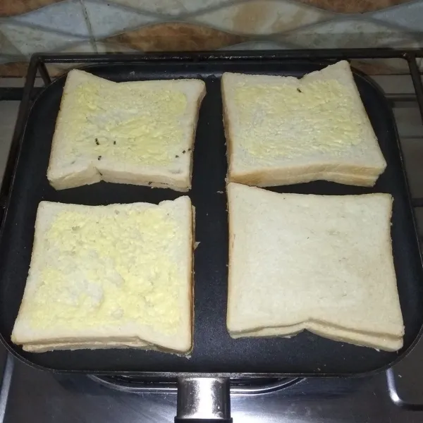 Siapkan teflon. Nyalakan api kecil. Lalu panggang roti tawar di atas teflon hingga kedua sisinya kecoklatan. Lalu iris melintang (seperti bentuk segitiga).