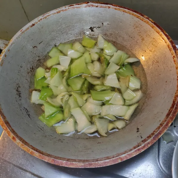 Tumis bawang merah dan bawang putih sampai harum. Masukkan batang sawi. Aduk-aduk. Tambahkan 2 gelas air. Biarkan mendidih.