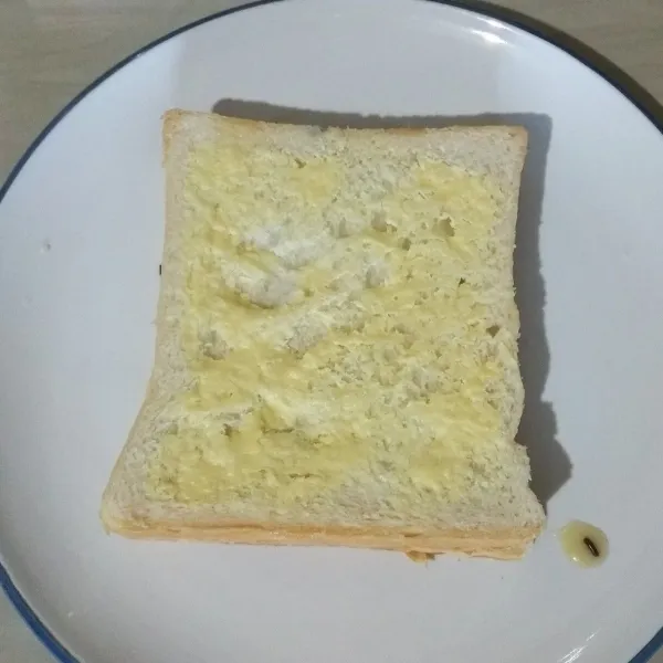 Lalu tutup rotinya (disatukan/ jadi bertumpuk roti yang ada toppingnya dengan roti yang hanya diberi margarin).