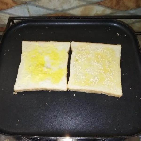 Oles margarin ke 2 sisi roti tawar. Taburi dengan wijen di satu sisi permukaannya. Lalu panggang roti tawar di atas teflon hingga berwarna kecoklatan/ permukaannya kering.