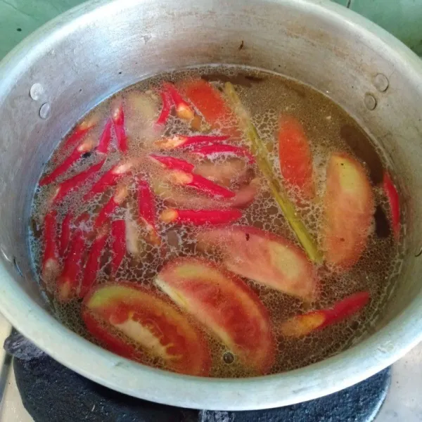 Setelah mendidih, masukkan potongan tomat, irisan cabe merah. Tambahkan air jeruk nipis.