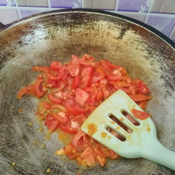 Masukkan irisan tomat, aduk rata. Masak sampai tomat layu. Bumbui dengan garam dan kaldu bubuk. Koreksi rasa.