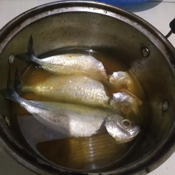 Masukkan ikan ke dalam panci, air, larutan asam jawa dan kunyit. Masak sampai mendidih.