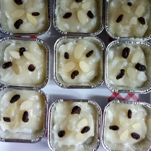 Tuang bahan topping ke adonan klappertaart. Taburi almond dan kismis.