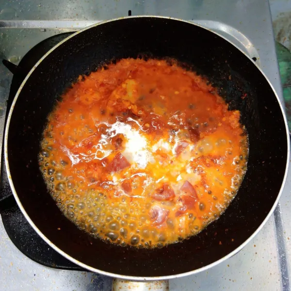 Masukkan tomat, gula merah, gula pasir, garam dan santan. Aduk rata. Masak sampai mendidih dan kuah menyusut. Kemudian siram di atas ayam goreng. Sajikan.