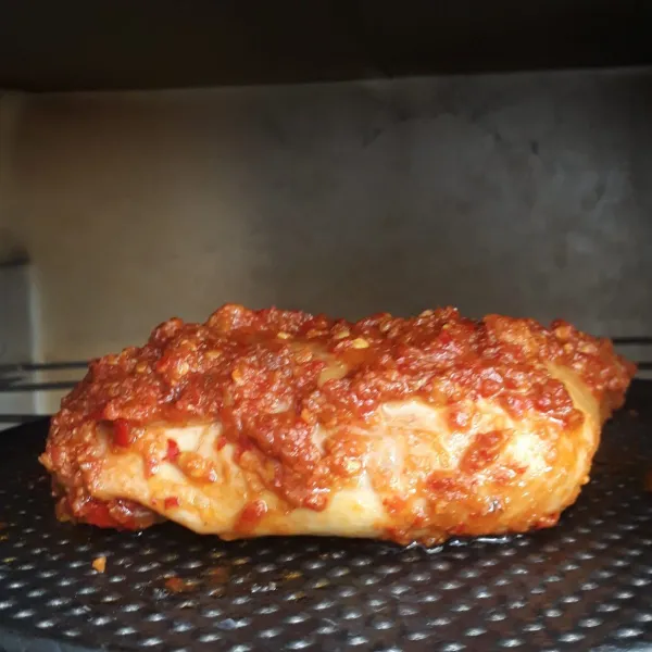 Letakkan daging ayam ungkep di atas loyang lalu oven selama 20 menit atau hingga agak kering.
